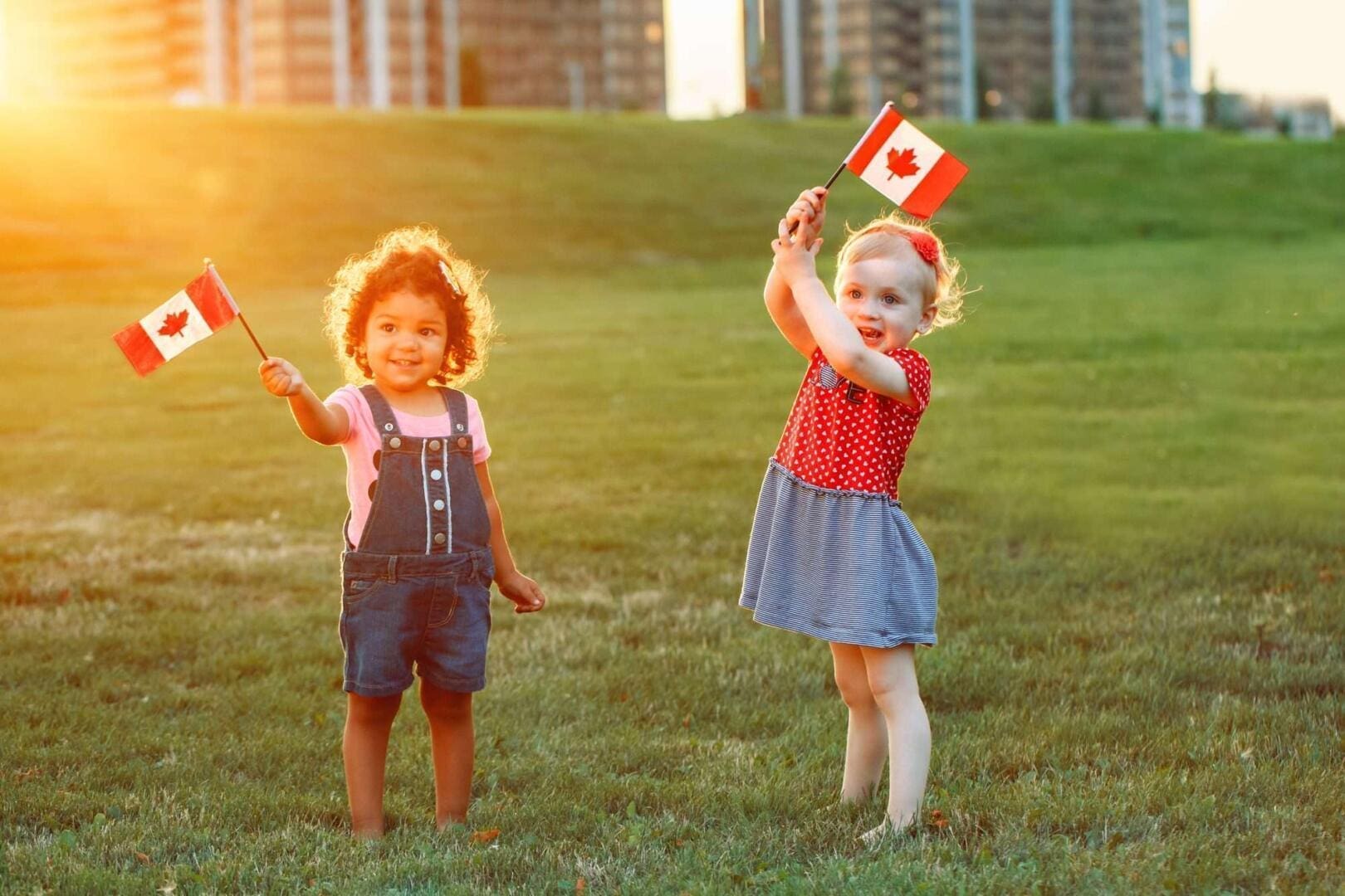 Happy adorable little blond Caucasian girl and boy smiling laughing holding hands and waving American flag outside celebrating 4th july Independence Day Flag Day concept.